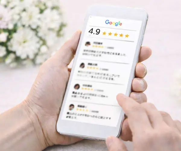 Google口コミ評価4.9を指し示すスマートフォンを持つ手