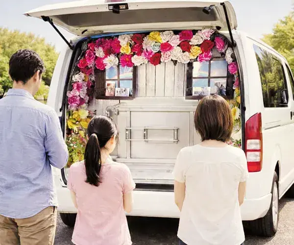 花で装飾された無煙無臭の高性能な移動火葬車で最後を見送るご家族の後ろ姿